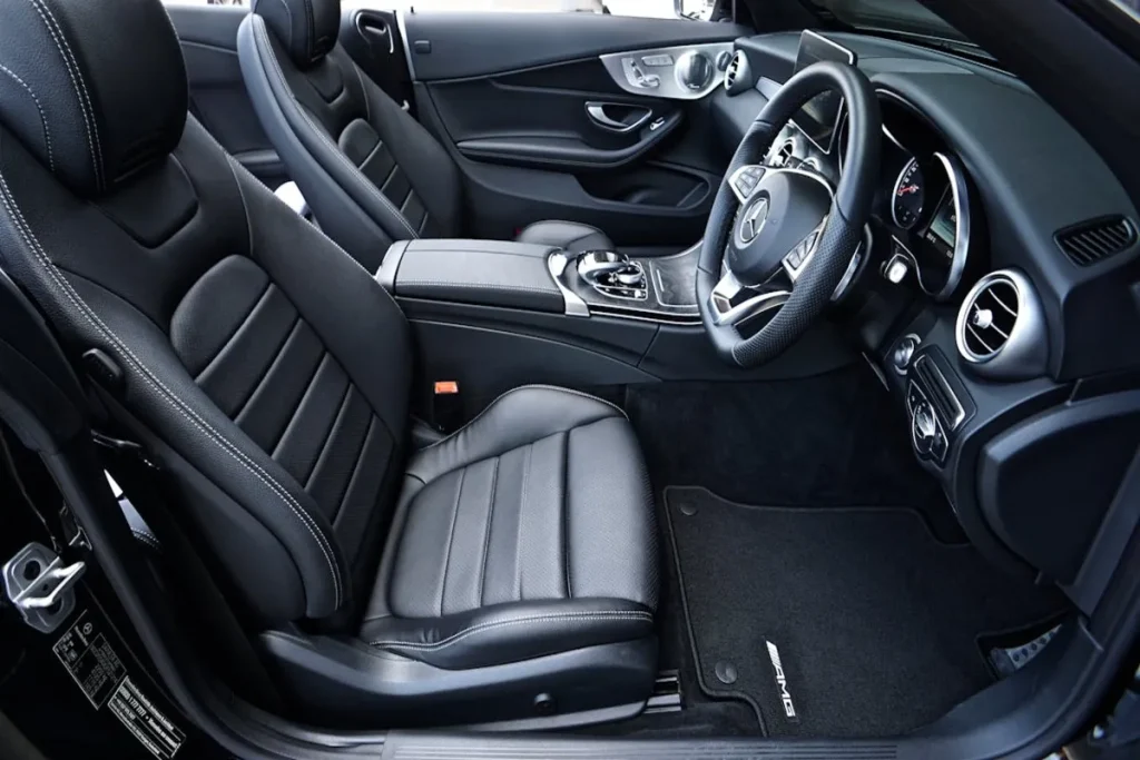 Interior de carro, com bancos de couro, painel e volante, destacando o estado de um veículo seminovos.