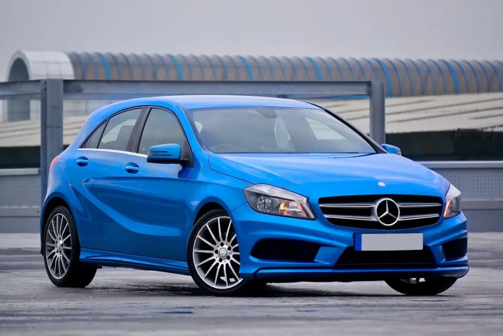 Carro Mercedes-Benz Classe A, modelo hatch na cor azul, com rodas esportivas e um fundo de estacionamento coberto. A imagem destaca um veículo seminovos de luxo.