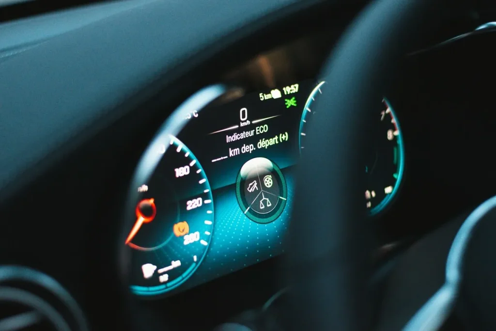 Painel digital de um carro de luxo moderno, mostrando o velocímetro, odômetro, indicadores de direção e informações do motor.