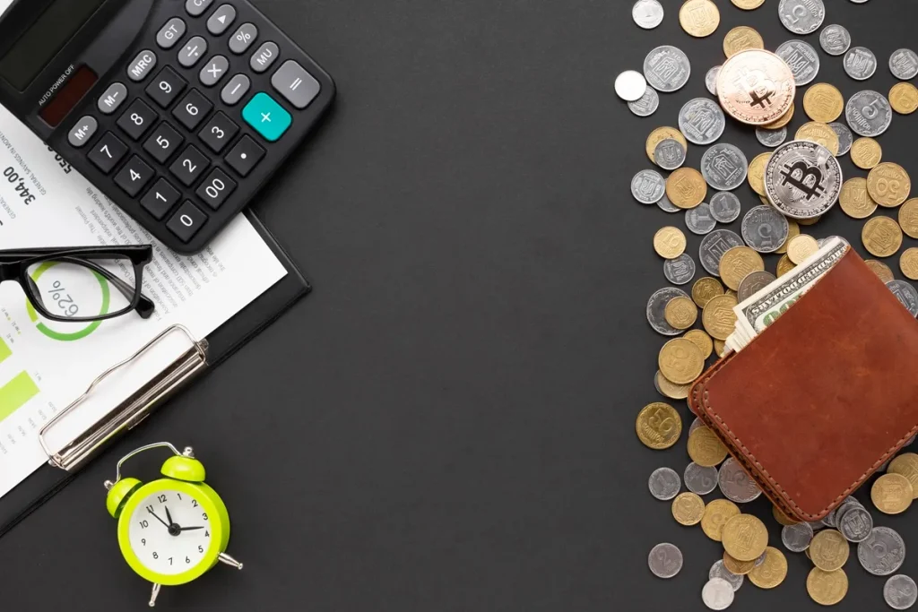 Imagem de itens relacionados a finanças pessoais, incluindo uma calculadora, moedas, uma carteira com dinheiro e gráficos financeiros
