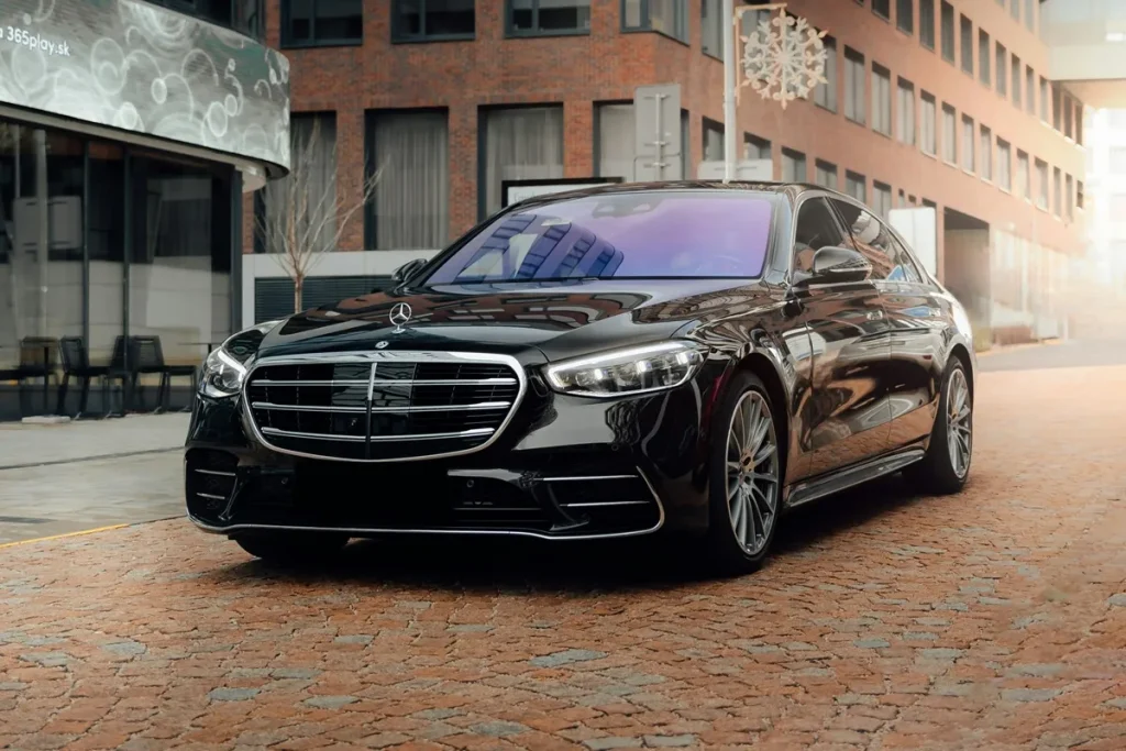 Mercedes-Benz S-Class preto, estacionado em uma rua de paralelepípedos, com design moderno e elegante, destacando a grade frontal da marca