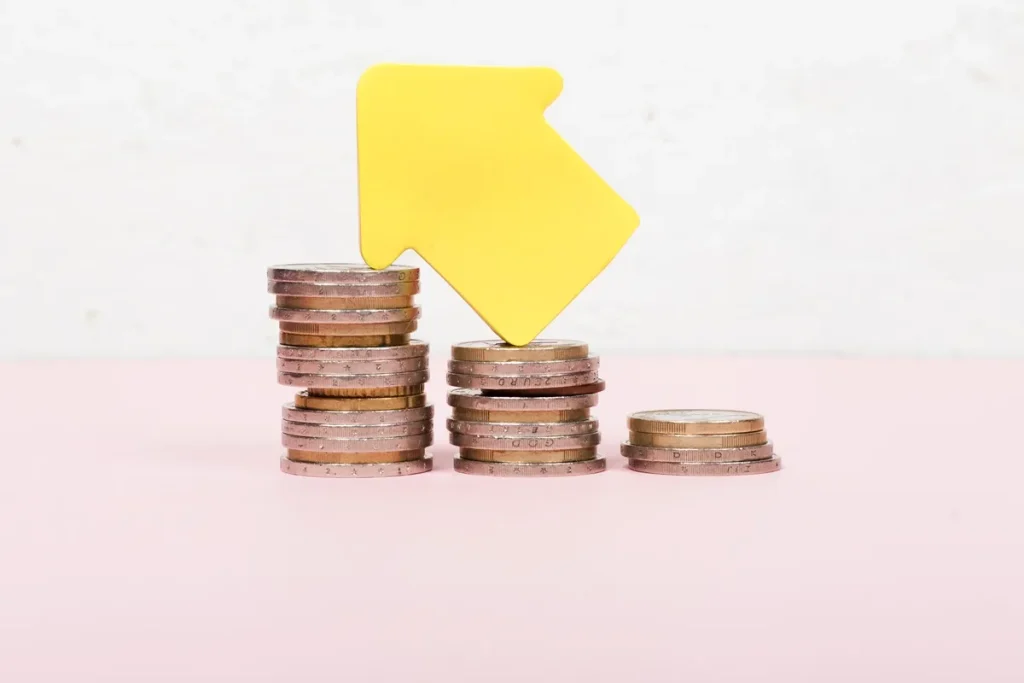 Seta amarela apontando para cima sobre pilhas de moedas, simbolizando o aumento da taxa SELIC e seus efeitos na economia.