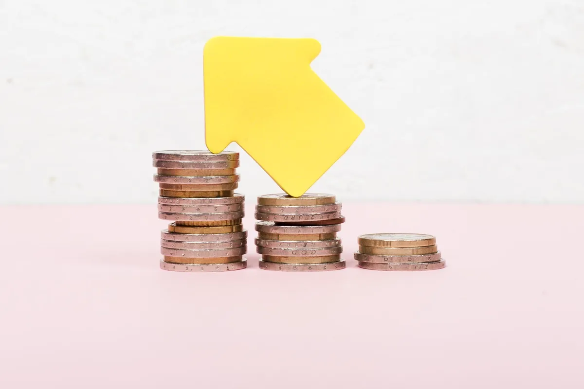 Seta amarela apontando para cima sobre pilhas de moedas, simbolizando o aumento da taxa SELIC e seus efeitos na economia.