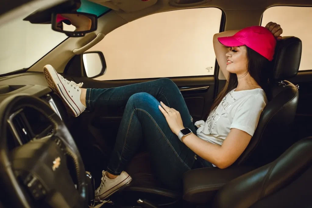 Mulher sorridente relaxa no carro novo, simbolizando a conquista do veículo com carta de crédito contemplada