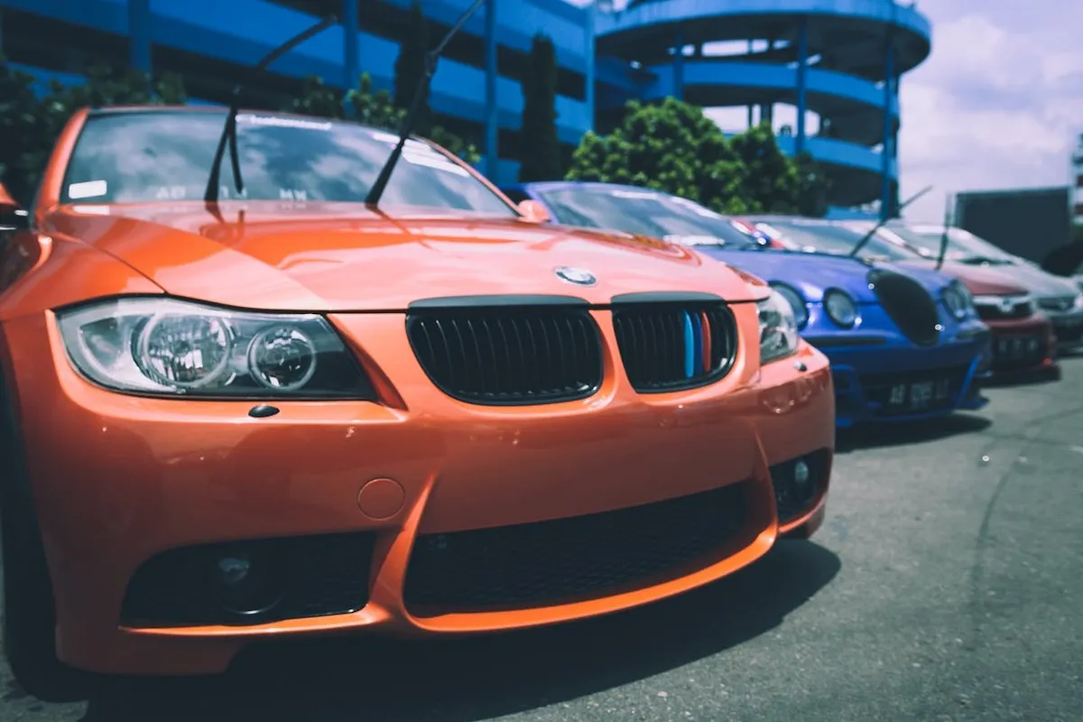 Carros esportivos estacionados em fila, incluindo um BMW laranja em destaque, representando a compra facilitada com carta de crédito contemplada.