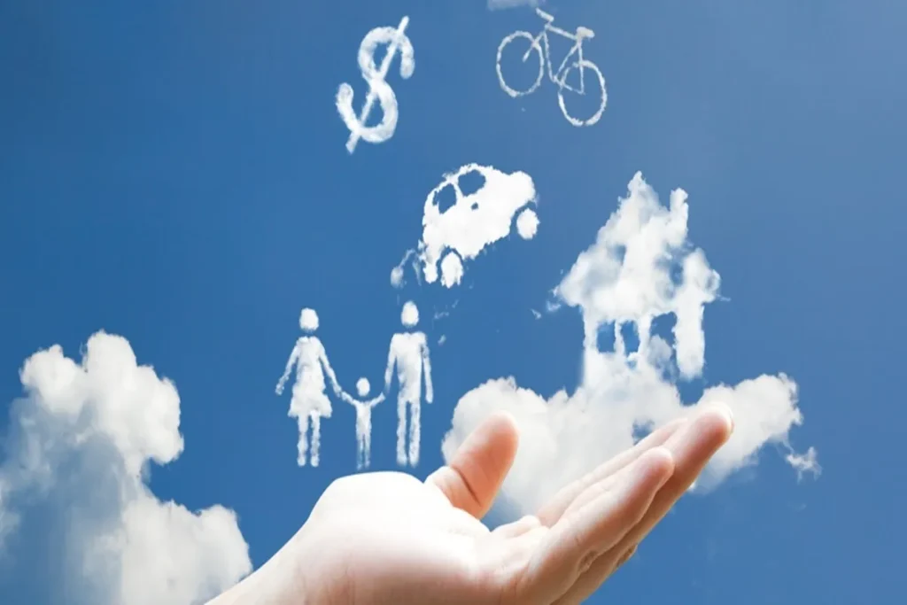 Mão estendida sob céu azul com nuvens formando símbolos de casa, carro, bicicleta, dinheiro e família, representando sonhos e conquistas.