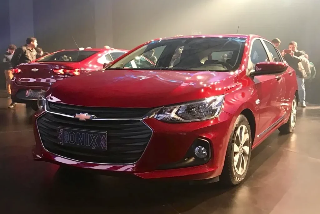 Novo Chevrolet Onix vermelho em destaque em evento de lançamento automotivo.