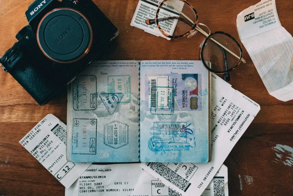 Passaporte com vistos e carimbos, câmera Sony, óculos e cartões de embarque sobre mesa de madeira