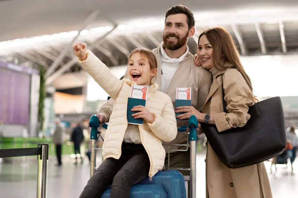 Família feliz no aeroporto com passagens de avião na mão, pronta para viajar graças ao consórcio para viagem.