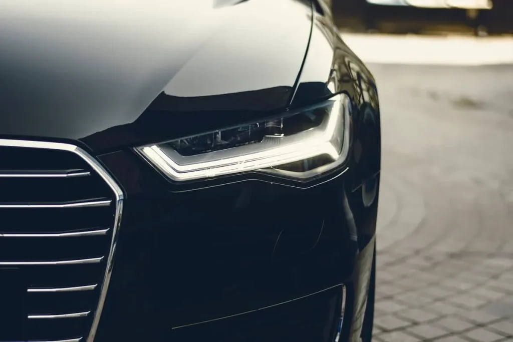 A frente de um carro preto com o farol aceso, representando a realização do sonho de comprar um veículo através de um consórcio e o momento de contemplação.