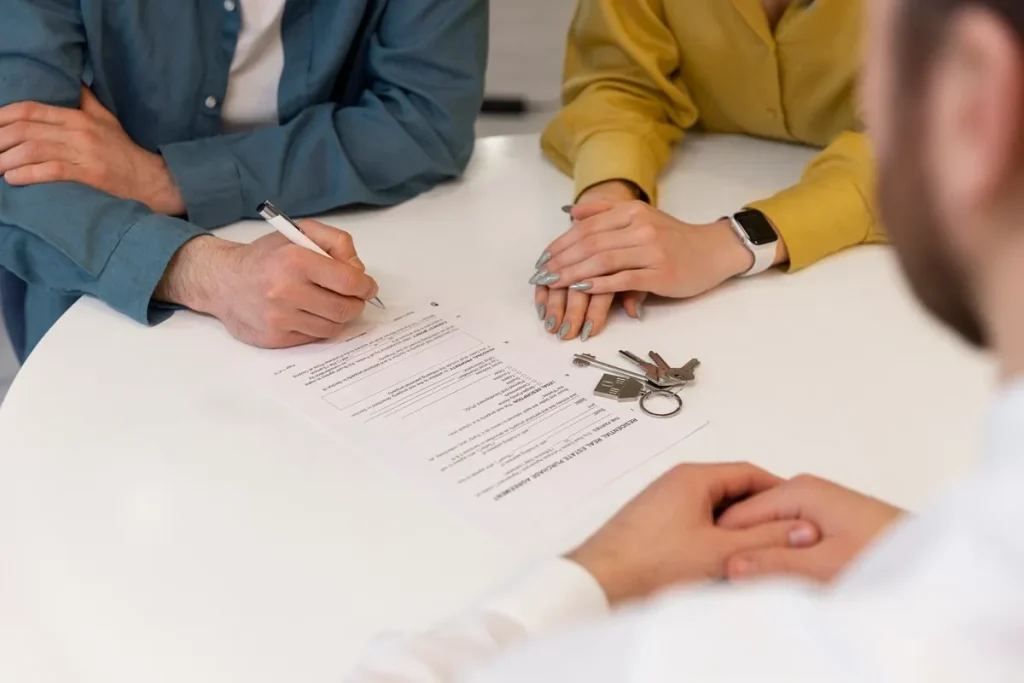 Casal assinando contrato de consórcio para a compra de um apartamento com chaves na mesa