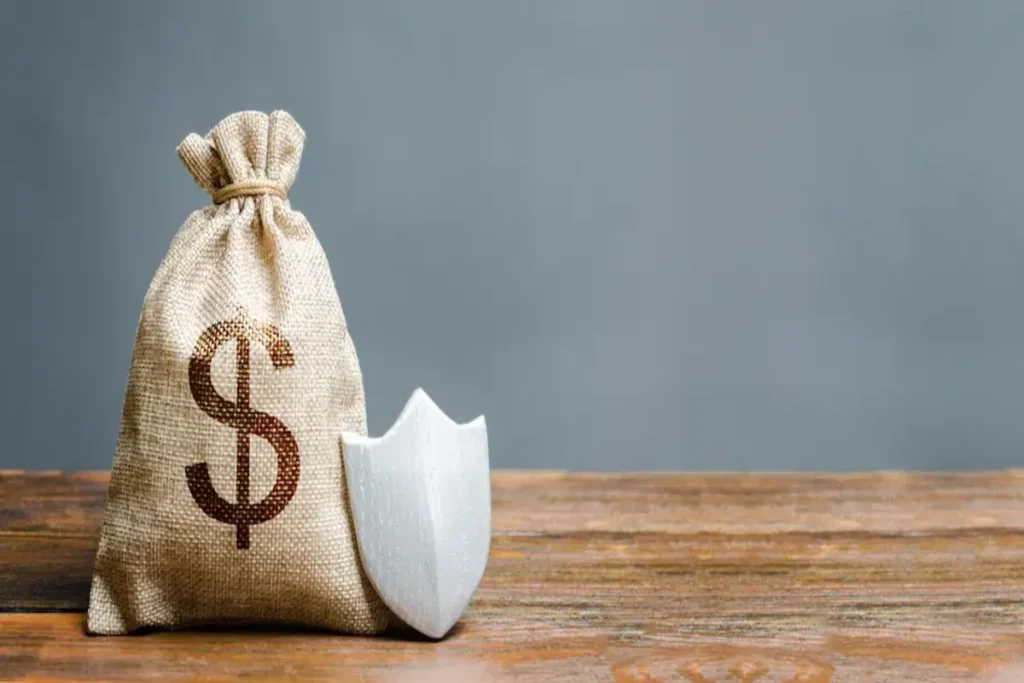 Saco de dinheiro com símbolo de cifrão e escudo branco representando proteção financeira