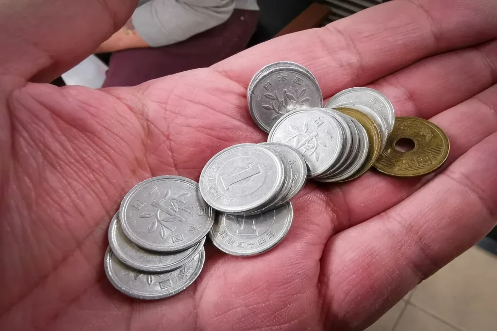 Mão segurando moedas metálicas simbolizando finanças pessoais e economia