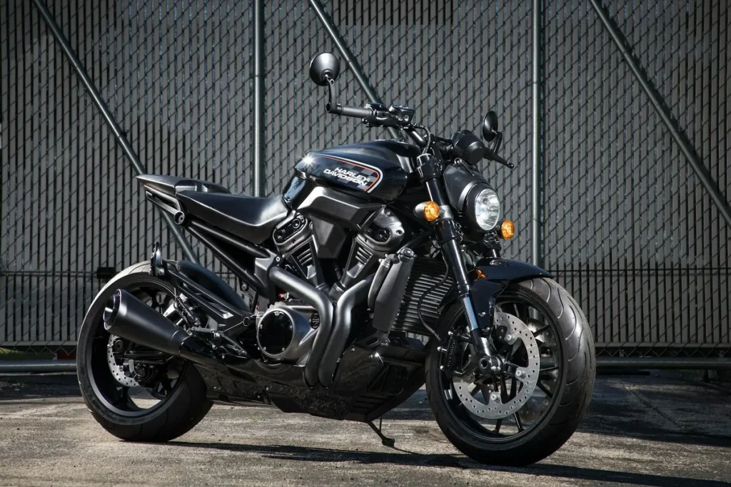 "Motocicleta Harley-Davidson preta estacionada em frente a uma cerca, representando um bem que pode ser objeto de alienação fiduciária em financiamentos de veículos."