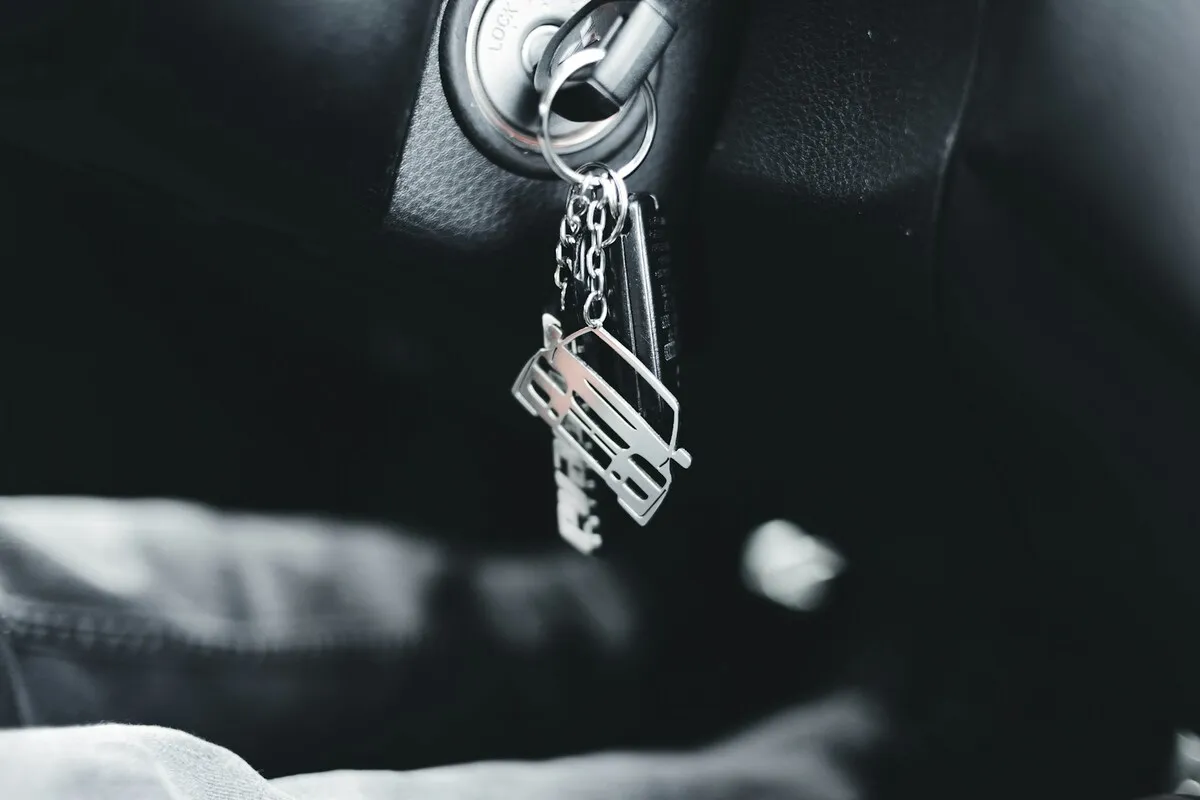 Chaves de carro com um chaveiro penduradas na ignição de um veículo, representando a posse de um bem que pode estar sob alienação fiduciária em um financiamento.