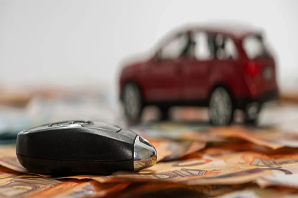 Chave de carro moderna sobre notas de dinheiro, com um carro miniatura desfocado ao fundo, simbolizando a carta de crédito e o poder de compra.