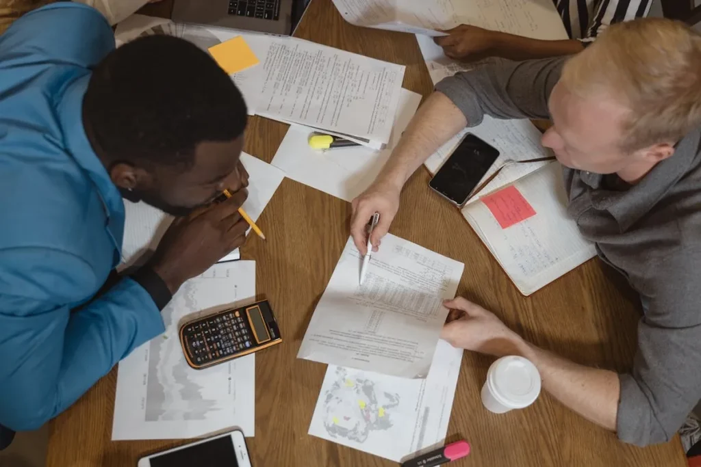 Duas pessoas analisando documentos e dados em uma mesa, representando a portabilidade de informações e trabalho colaborativo.