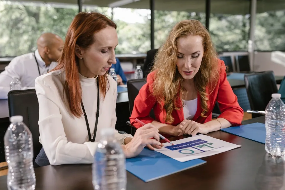 "Duas mulheres em reunião de negócios analisando documentos, refletindo a portabilidade de ideias e informações em ambientes corporativos."