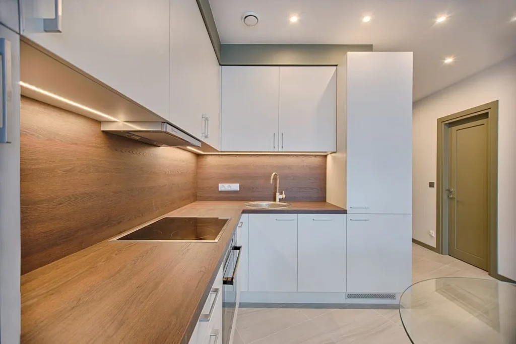 Cozinha moderna e funcional, com bancadas de madeira, armários brancos e iluminação de LED, ideal para um apartamento na planta.