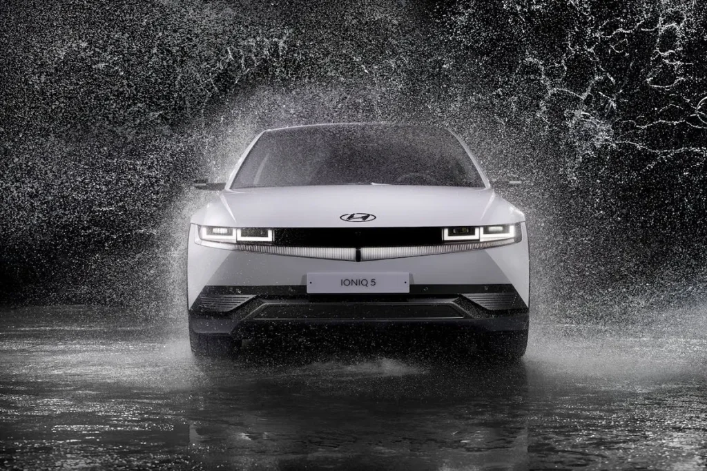 Carro elétrico Hyundai Ioniq 5 branco em close-up, visto de frente, com água respingando ao redor.