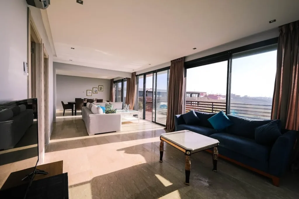 Uma sala de estar em um apartamento de luxo, com grandes janelas, sofás modernos e iluminação natural. A imagem destaca a importância de um projeto de casa planejada.