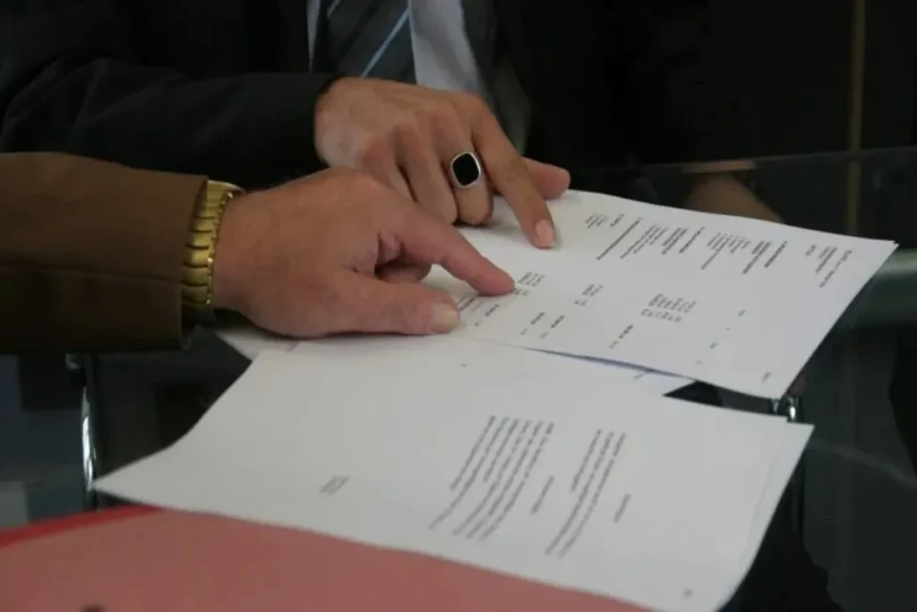 Duas pessoas analisando documentos financeiros e contratos, representando como funciona a carta de crédito.