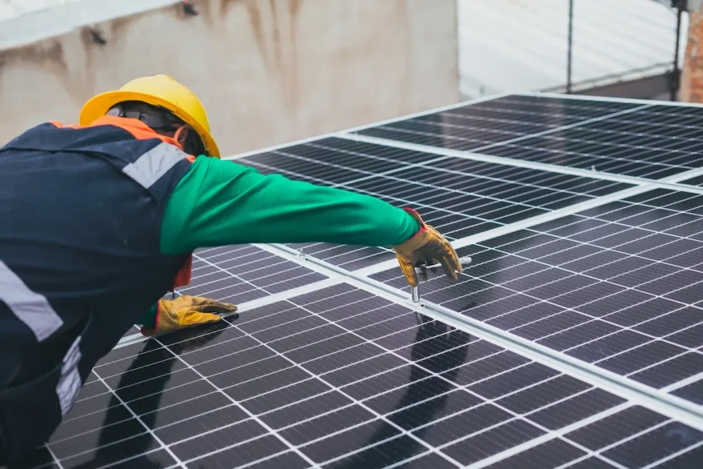 écnico usando luvas de proteção instalando ou inspecionando painéis solares em um telhado.