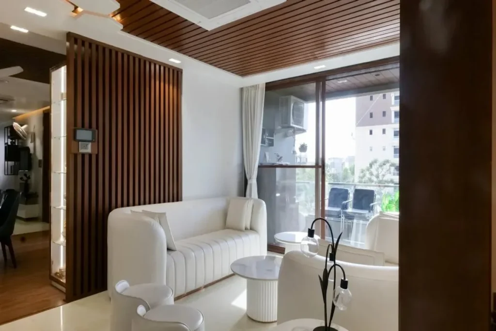 Studio moderno com sofá branco e painel ripado de madeira. A imagem foca na decoração, no design e na otimização de espaço para studios.
