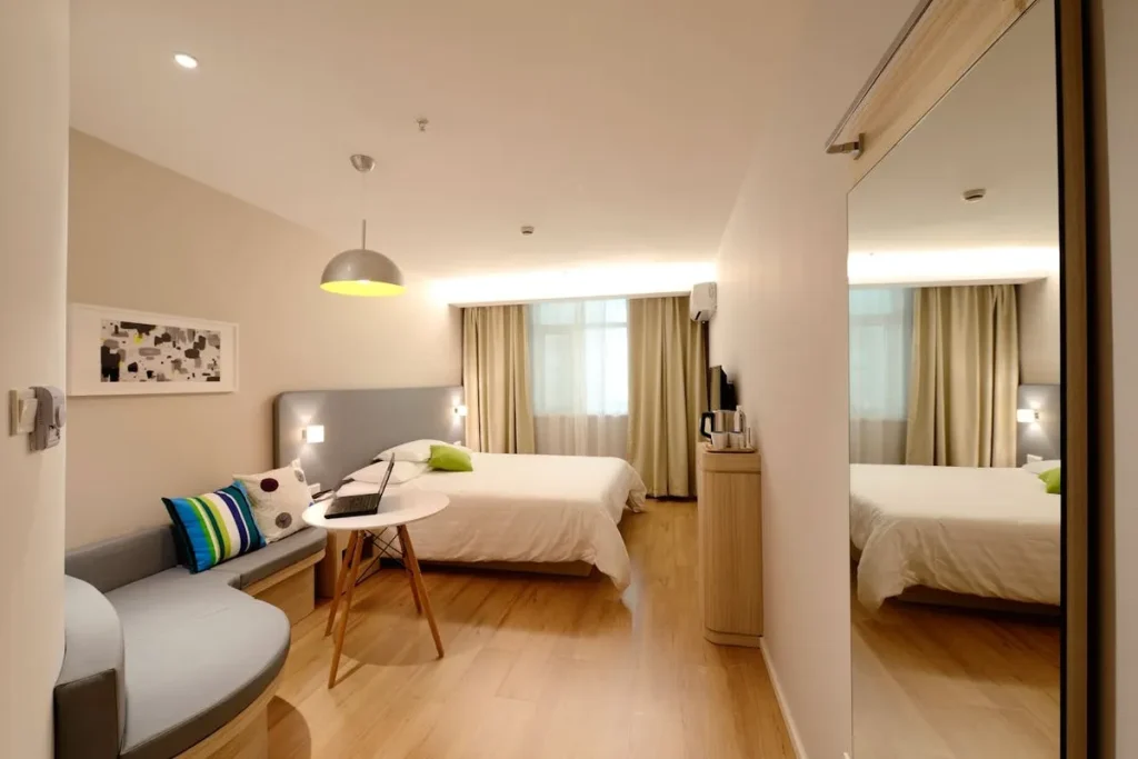 Studio moderno com cama de casal, sofá cinza e mesa de apoio. A imagem foca na decoração, no design e na otimização de espaço para studios.