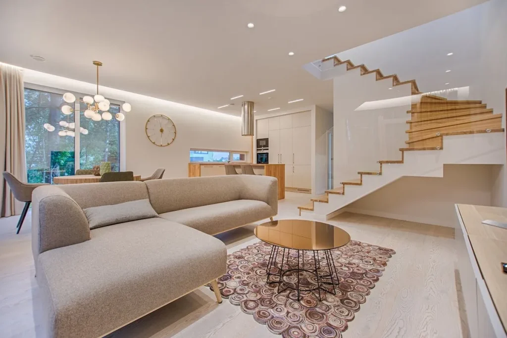 Studio duplex moderno, com sala de estar e cozinha integrada, escada de madeira, sofá modular e luminária de design. A imagem destaca a otimização do espaço, a decoração e o design.