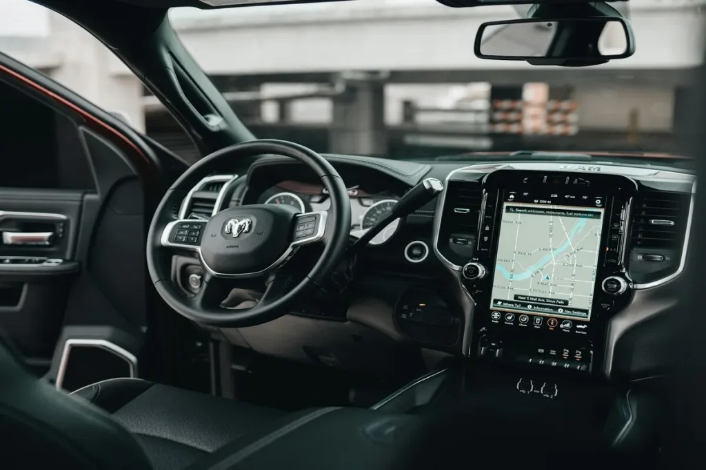 Interior de uma picape Ram, com o painel de controle, volante e tela sensível ao toque do sistema de navegação.
