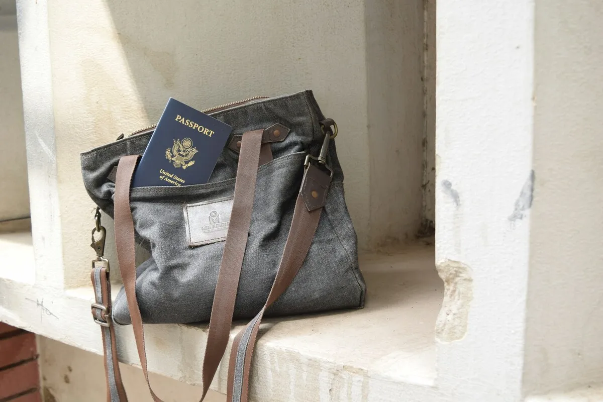 Um passaporte dos Estados Unidos dentro de uma bolsa de viagem de tecido cinza, pronta para uma viagem internacional.