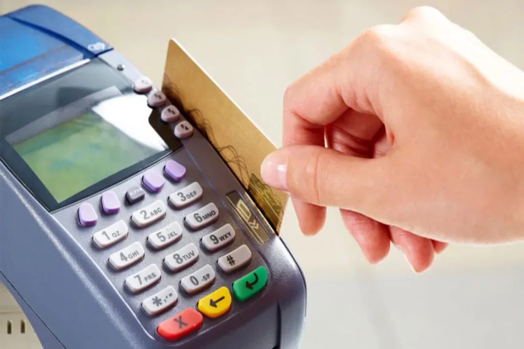 Pessoa passando cartão em maquininha, representando pagamentos e autofinanciamento.