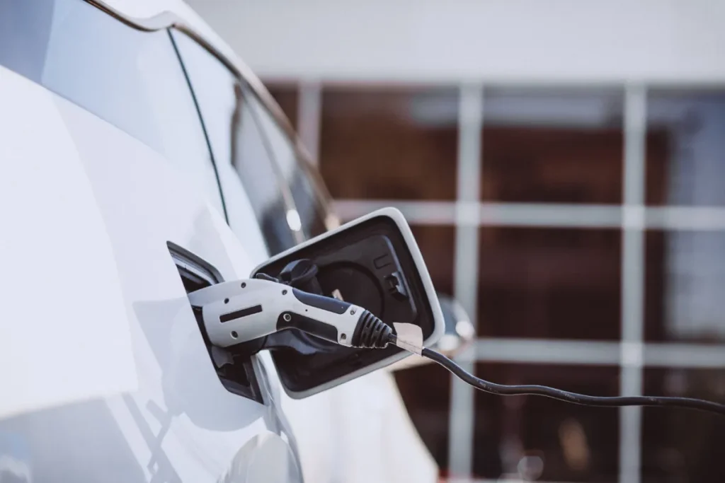 Plugue de uma estação de carregamento conectado a um carro elétrico branco.