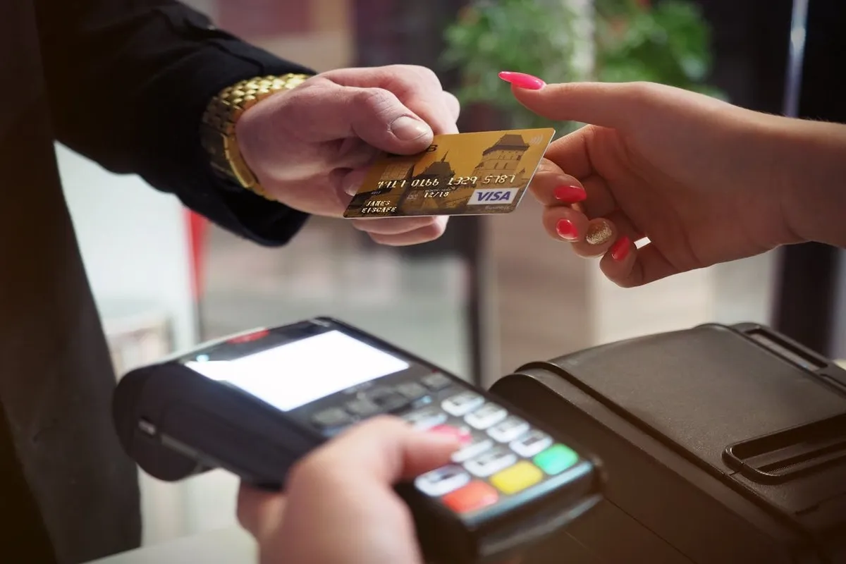 Uma pessoa entrega um cartão de crédito internacional Visa a outra pessoa em uma transação.