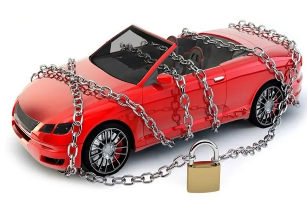 Um carro esportivo vermelho de brinquedo envolto em correntes de metal com um cadeado dourado, simbolizando o bloqueio judicial (RENAJUD), a restrição de circulação e a impossibilidade de transferência de propriedade de um veículo.