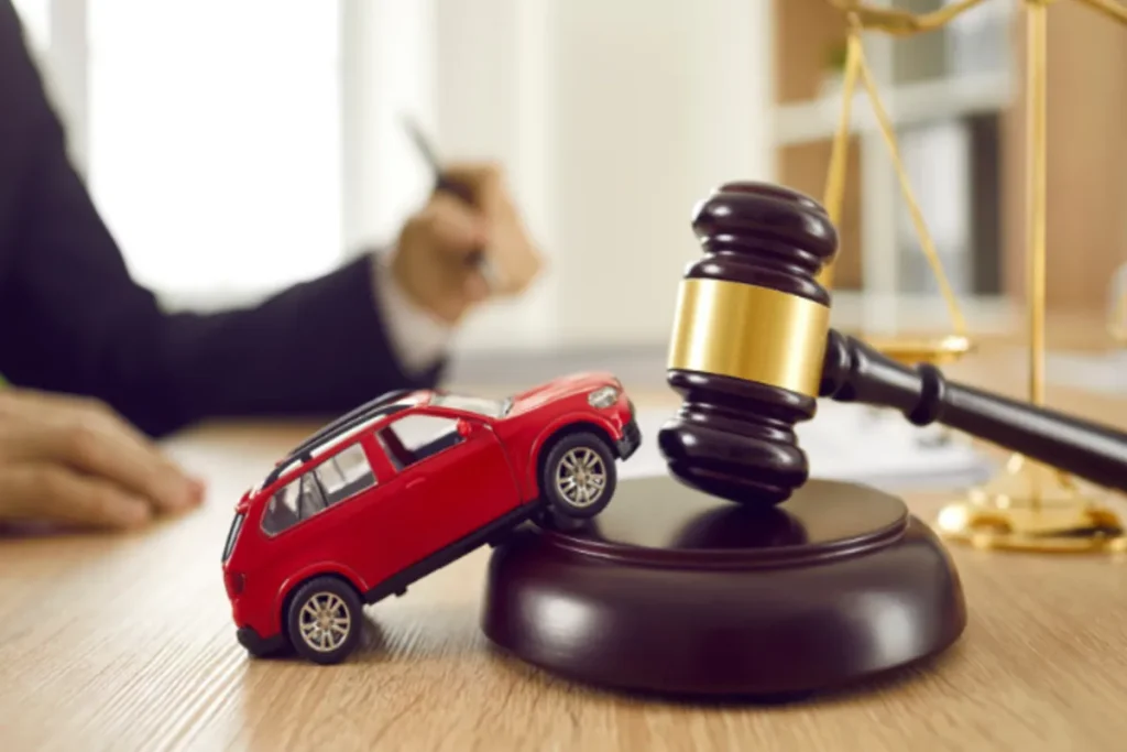 Um martelo de juiz (malhete) e um carro de brinquedo vermelho em cima de uma mesa de escritório, simbolizando a apreensão ou bloqueio judicial de veículos através do sistema RENAJUD e a relação entre direito e propriedade veicular.
