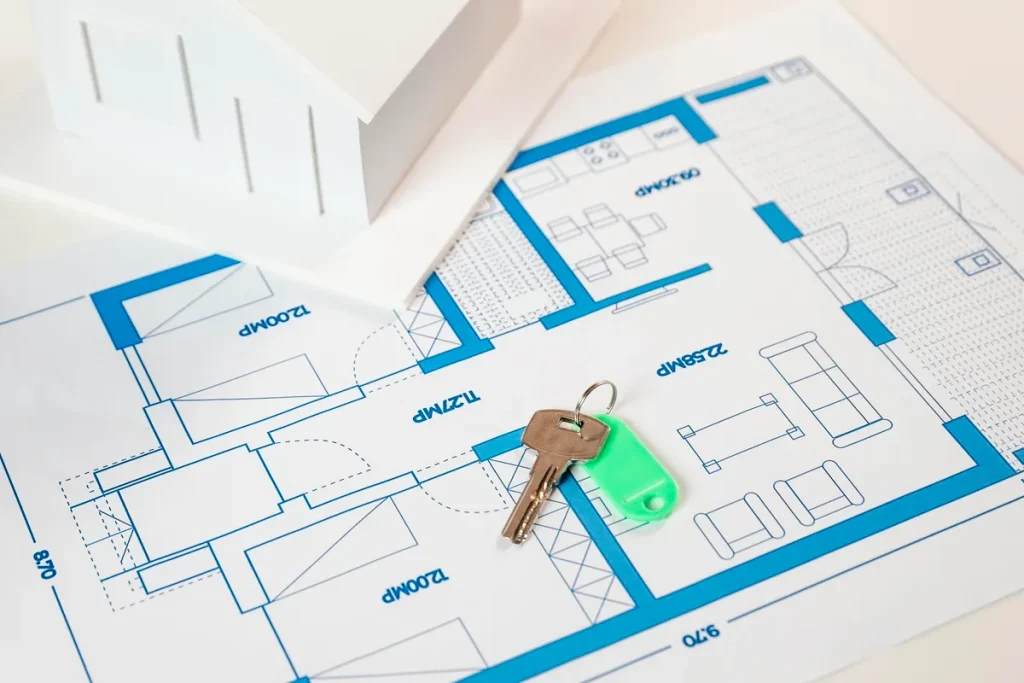 Chaves sobre planta baixa de imóvel com miniatura de casa, representando compra de imóveis na planta e planejamento residencial.