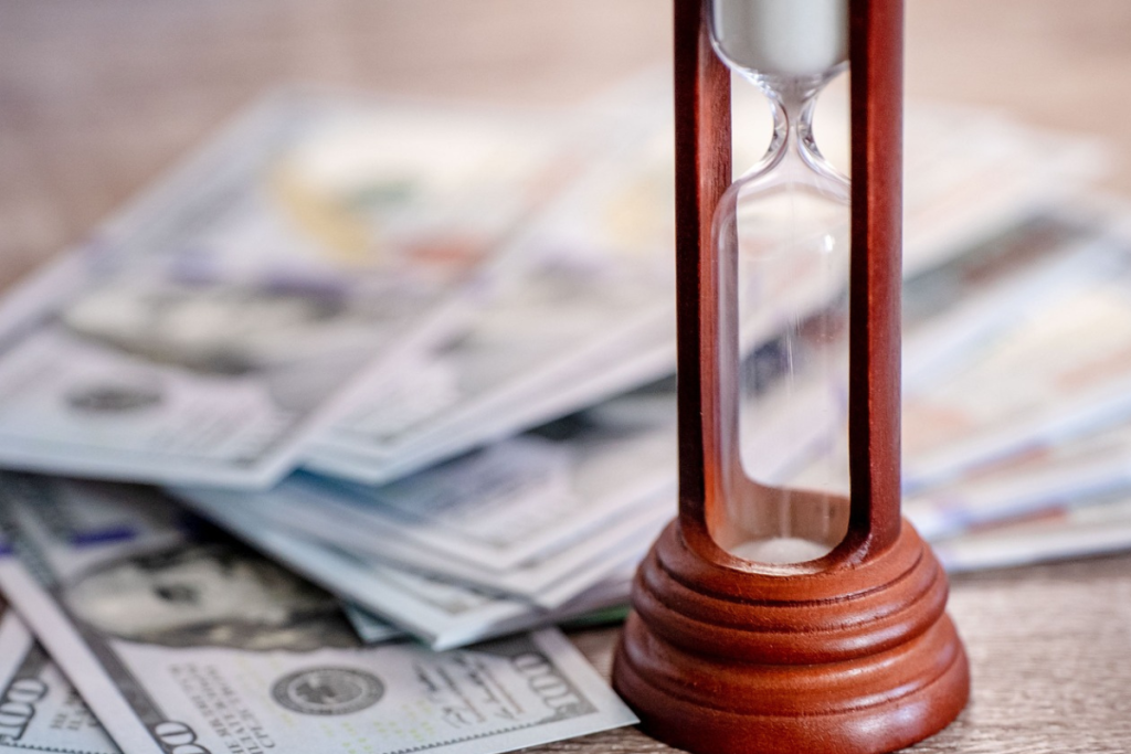 Cédulas espalhadas do lado de uma ampulheta