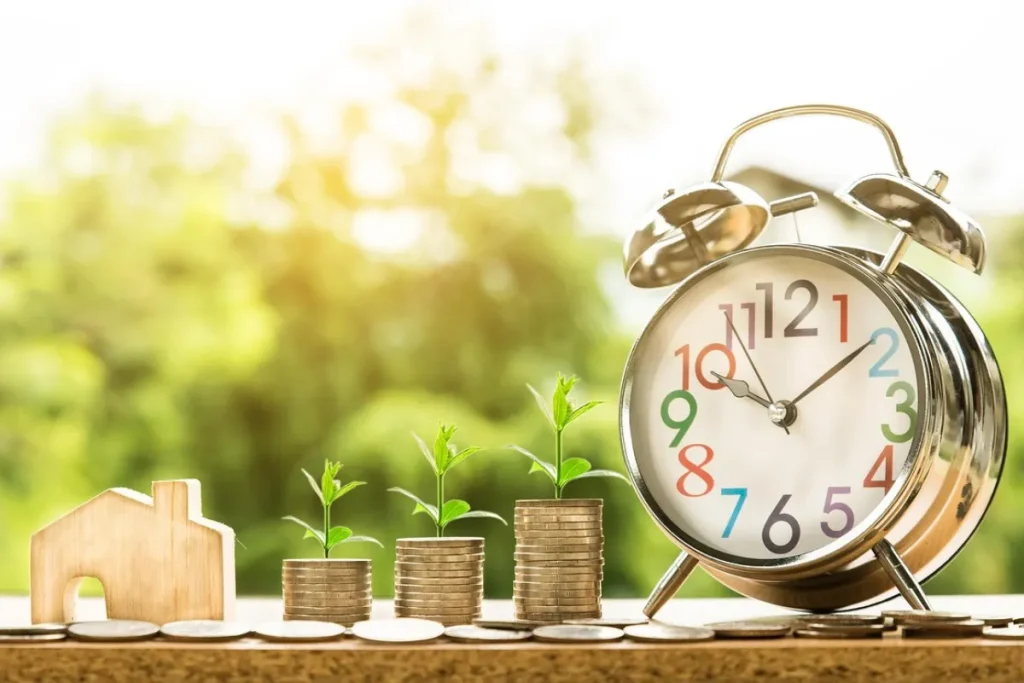 Moedas empilhadas e um relógio do lado