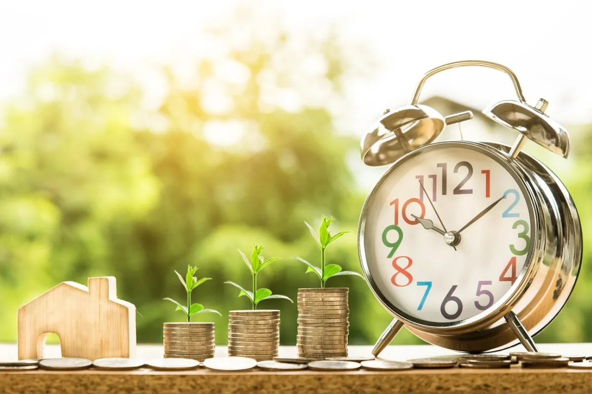 Moedas empilhadas e um relógio do lado