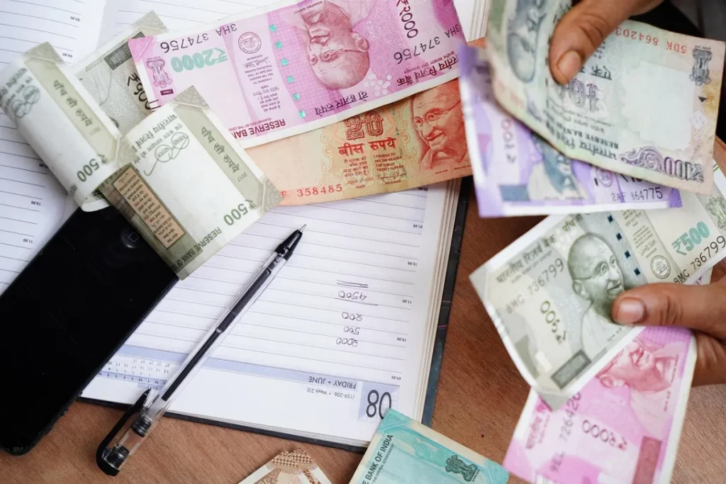 Caderno em uma mesa, com várias cédulas espalhadas